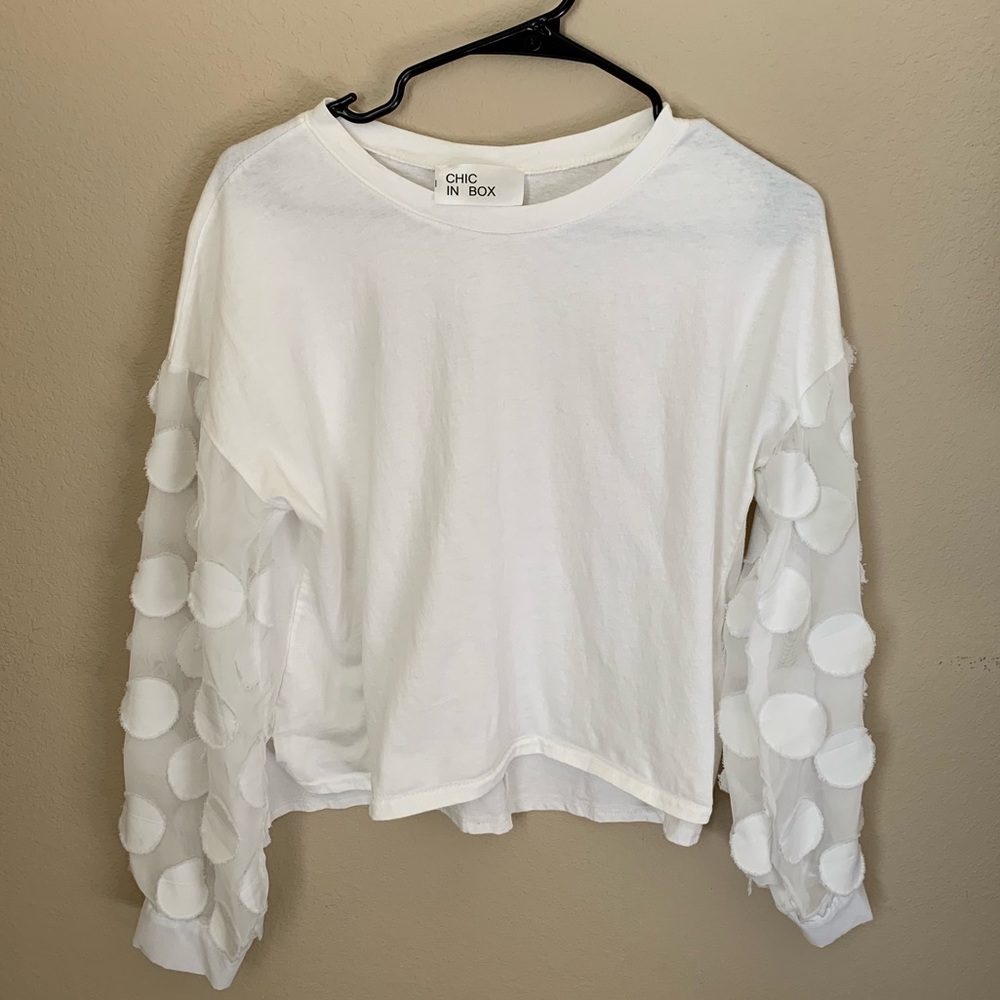 A long sleeved white shirt with frill on sleeves